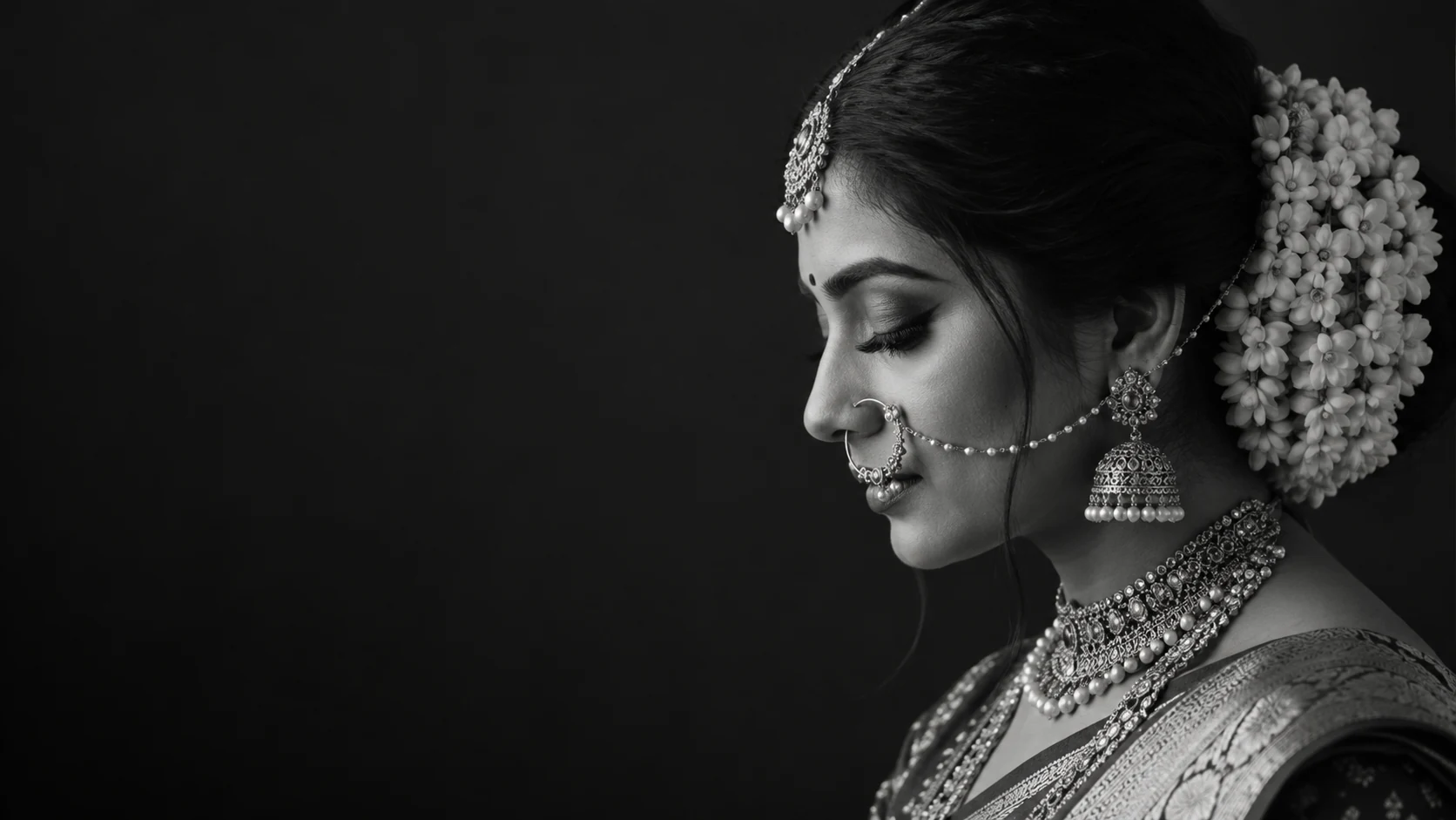 Black-and-white side profile of an Indian bride with jasmine in her hair and intricate bridal jewellery
